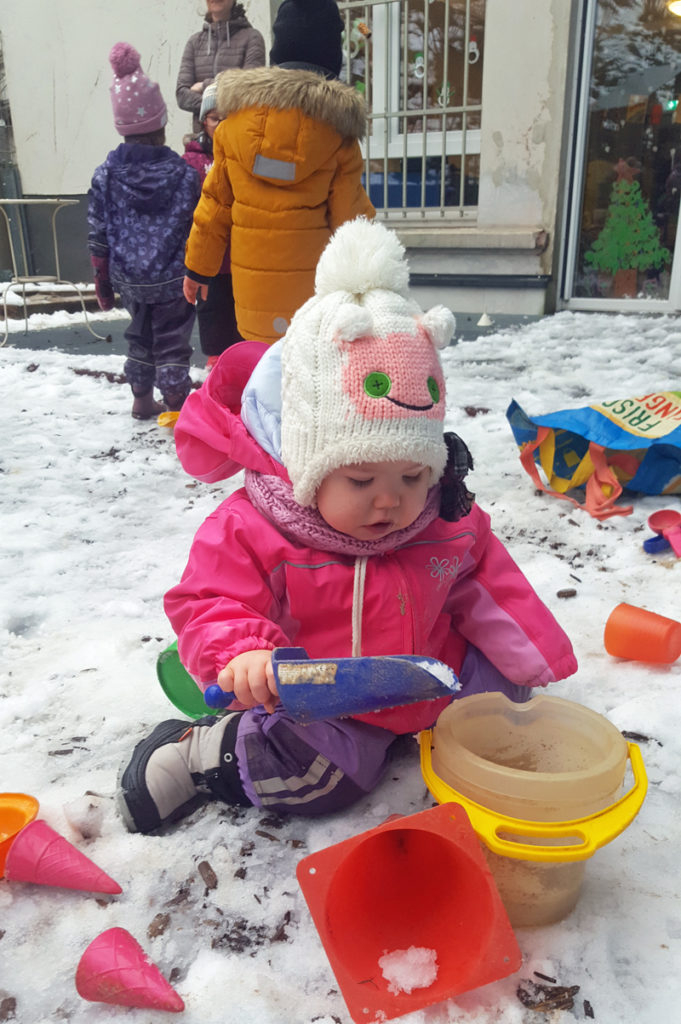 Kinder der CVJM-Kita Oberbarmen spielen am Haus im Schnee
