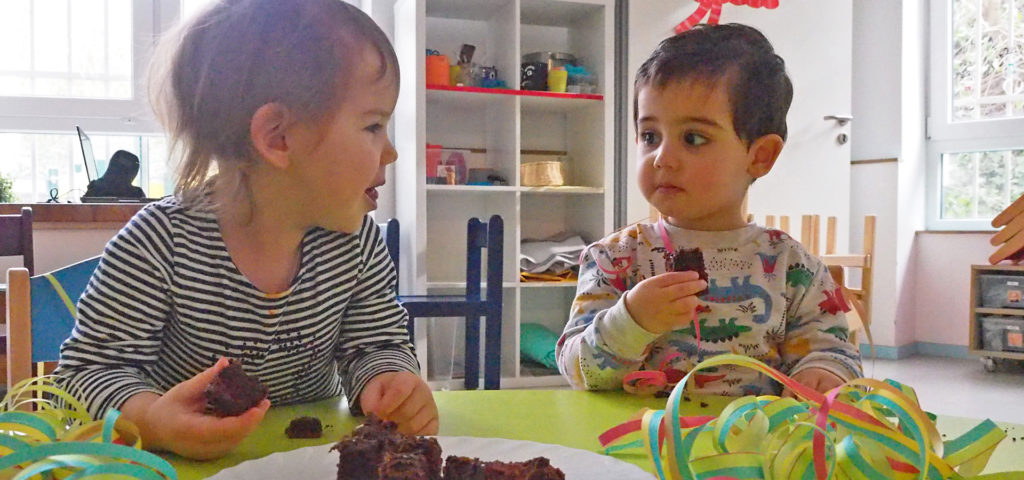 zwei-kinder-essen-schokoladenkuchen-am-tisch