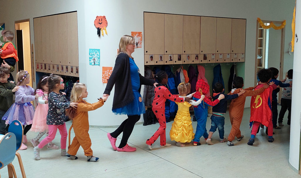 kinder und eine erzieherin machen eine polonaise