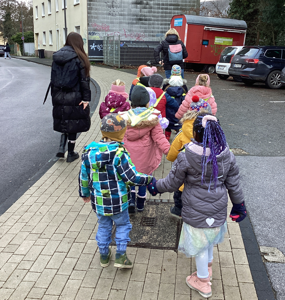 eine-kindergruppe-geht-in-zweierreihen-ueber-den-gehweg