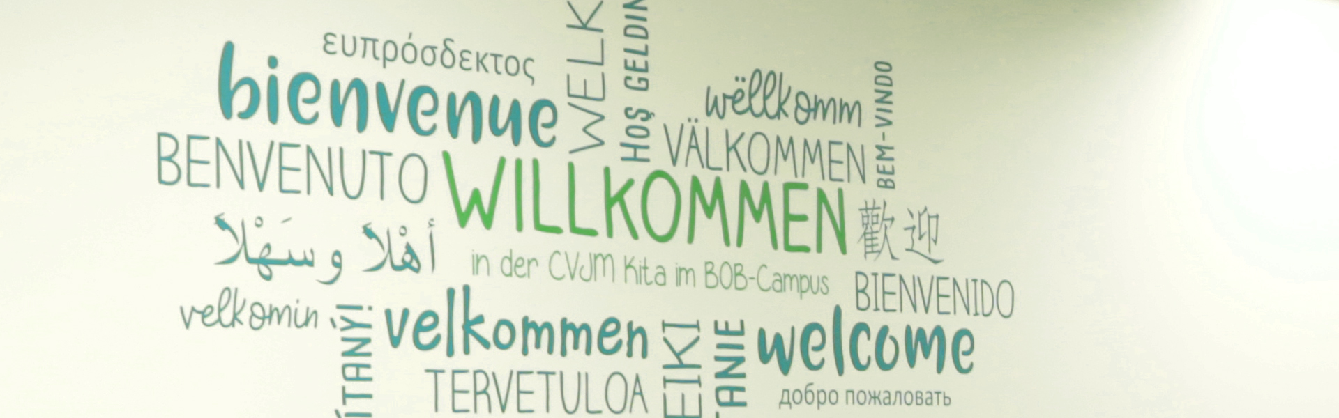 Wortwolke auf weisser Wand mit dem Wort Willkommen in verschiedenen Sprachen