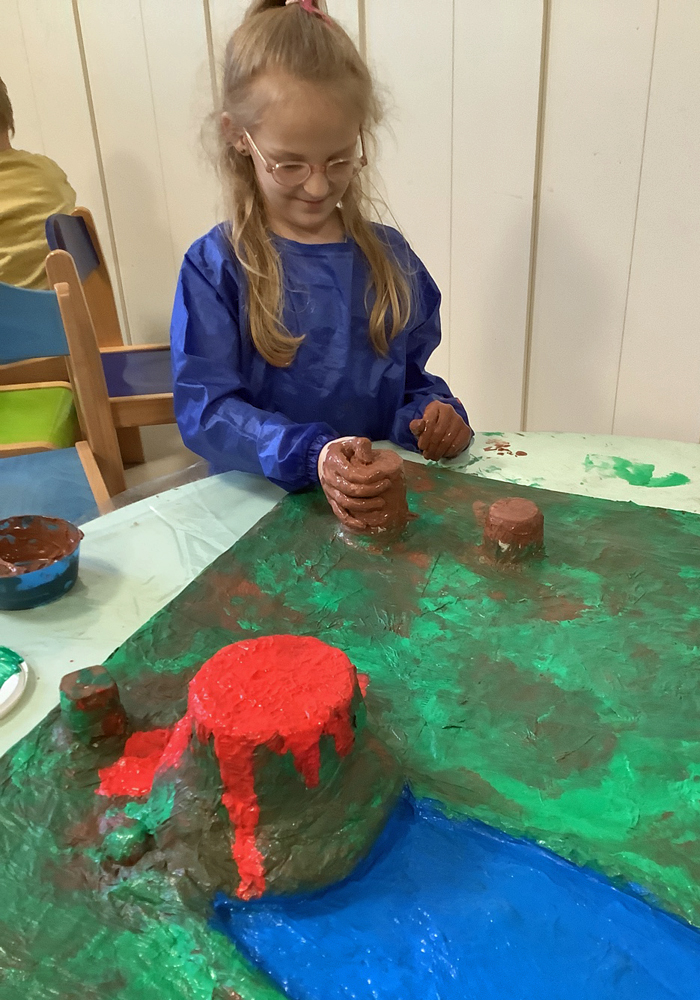 Ein Kind mal mit Fingerfarben eine Pappmasche-Landschaft an
