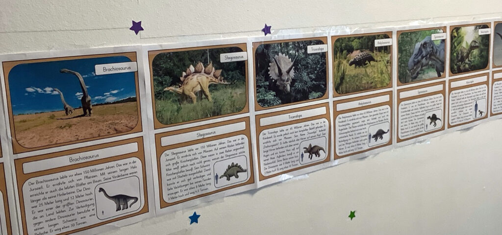 An der Wand haengen Bilder von Dinosauriern nebeneinander