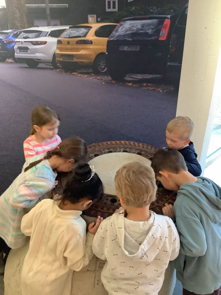 Kinder schauen durch die Loecher eines Gullideckels im Naturmuseum Dortmund