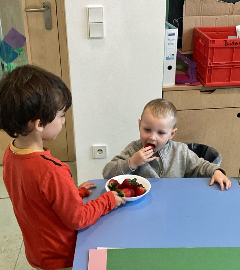 Kinder essen am Tisch Erdbeeren