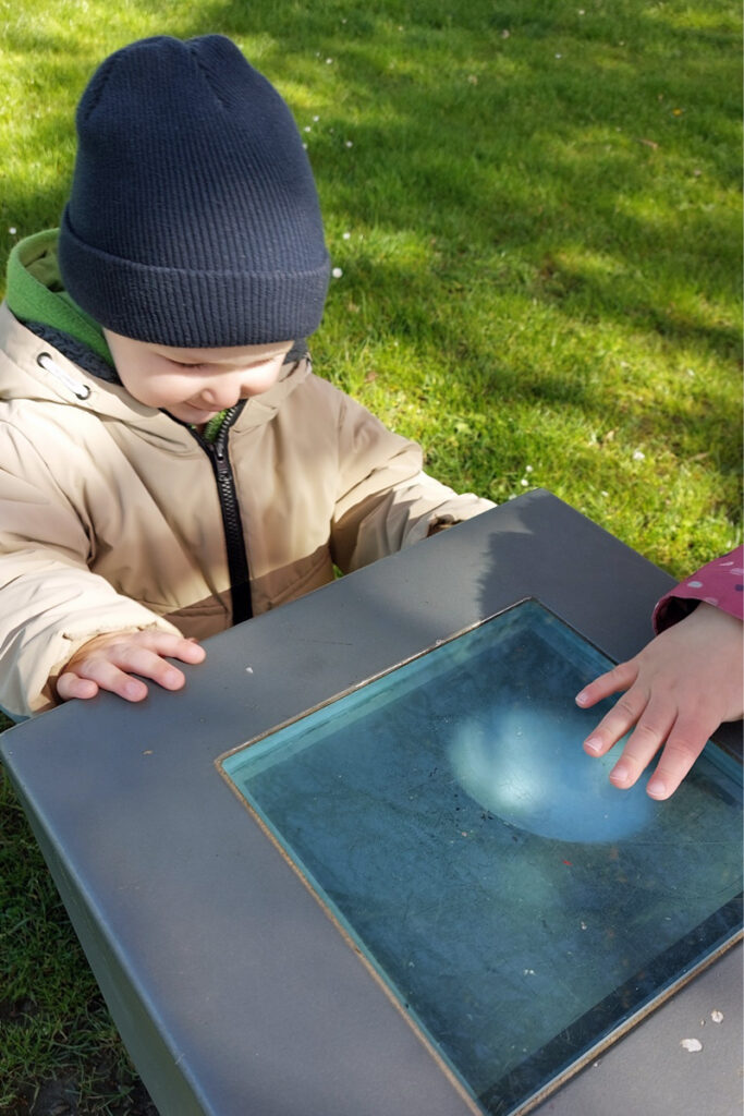 Kinder schauen sich ein Kunstobjekt in einem Park an