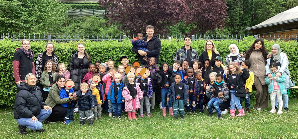 Kinder und Erwachsene haben sich zu einem Gruppenbild aufgestellt und schauen in die Kamera