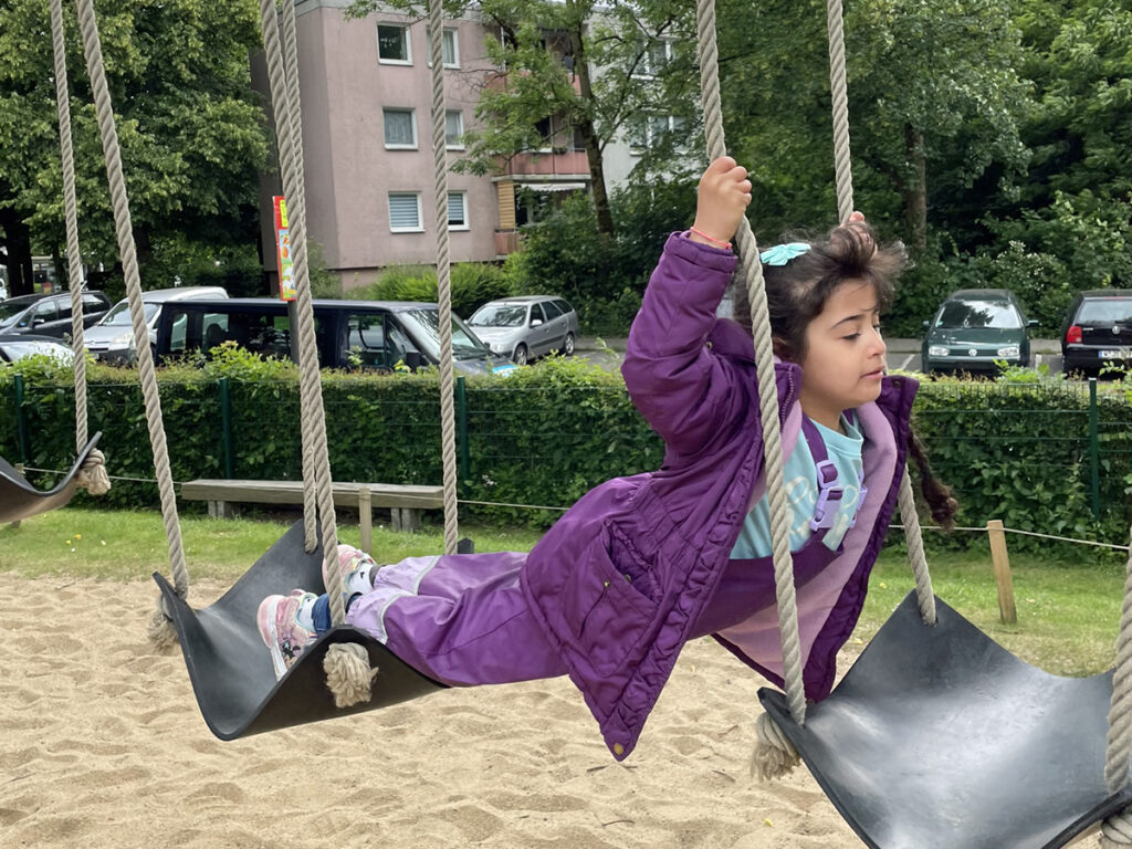 Ein Kind klettert auf einem Spielgeraet aus Seilen und kleinen Plastikebenen