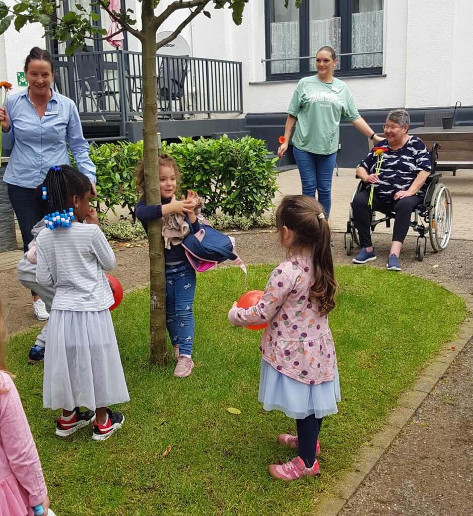 Kinder und Erwachsene spielen mit Luftballons in einem kleinen Garten