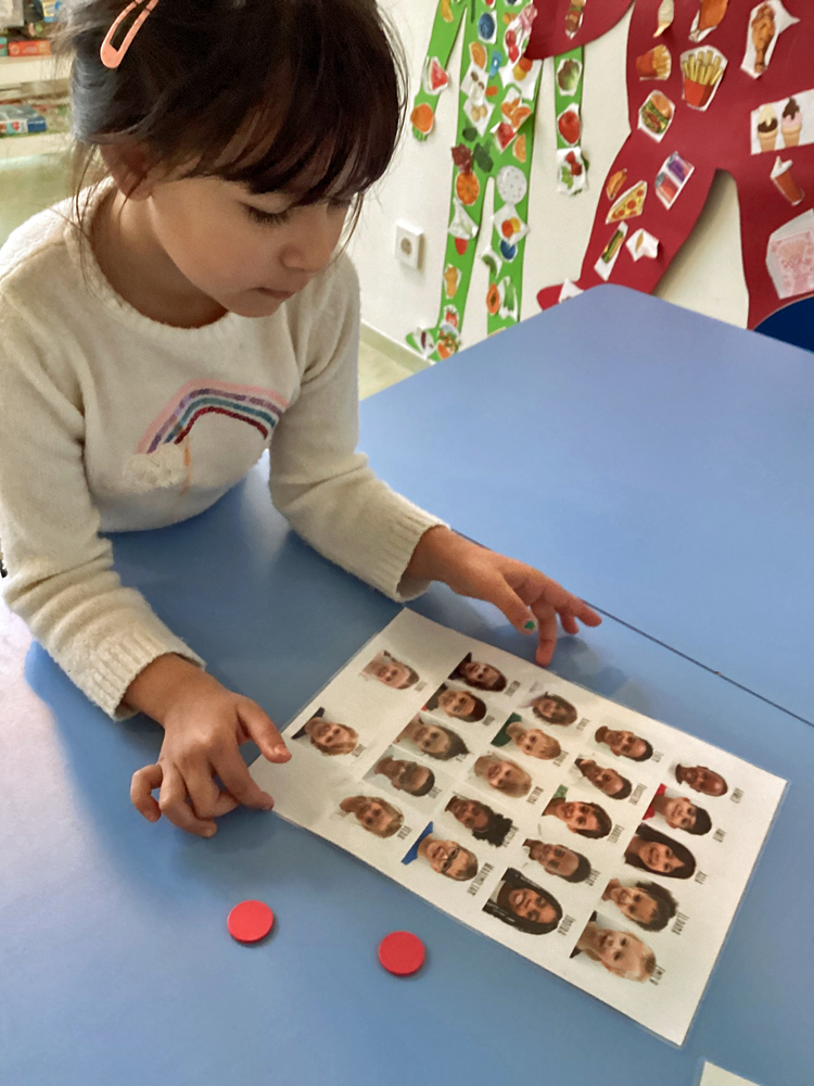 Zwei rote Plastikchips liegen auf einem Tisch neben einem Blatt mit den Portraits von Kindern