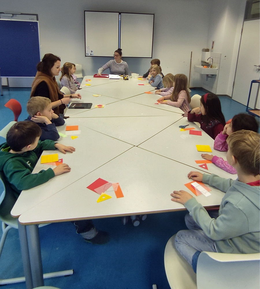 Kinder und eine Erzieherin sitzen am Tisch in der Junioruni Wuppertal