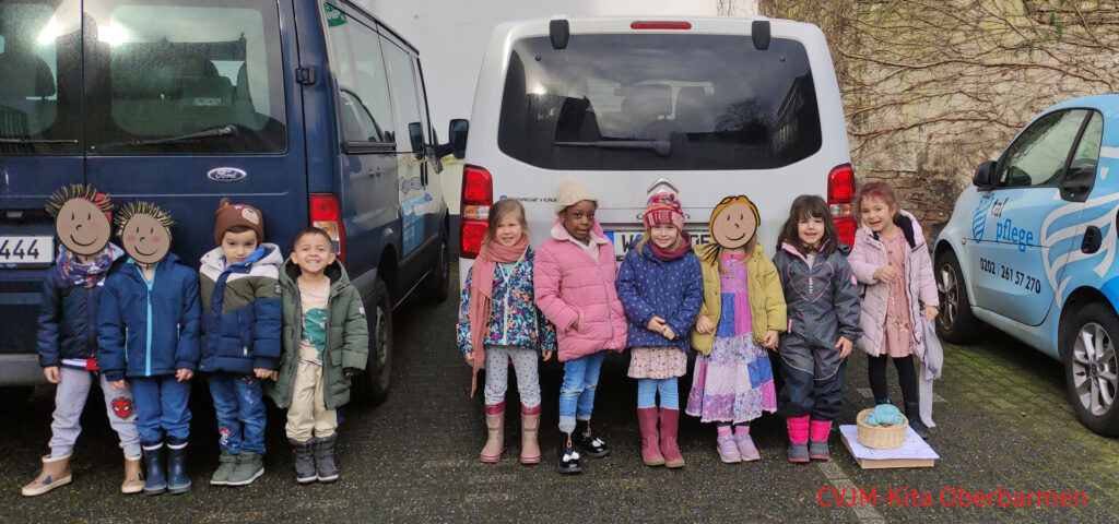 Kinder stehen vor zwei Mehrsitzer-Fahrzeugen und schauen in die Kamera