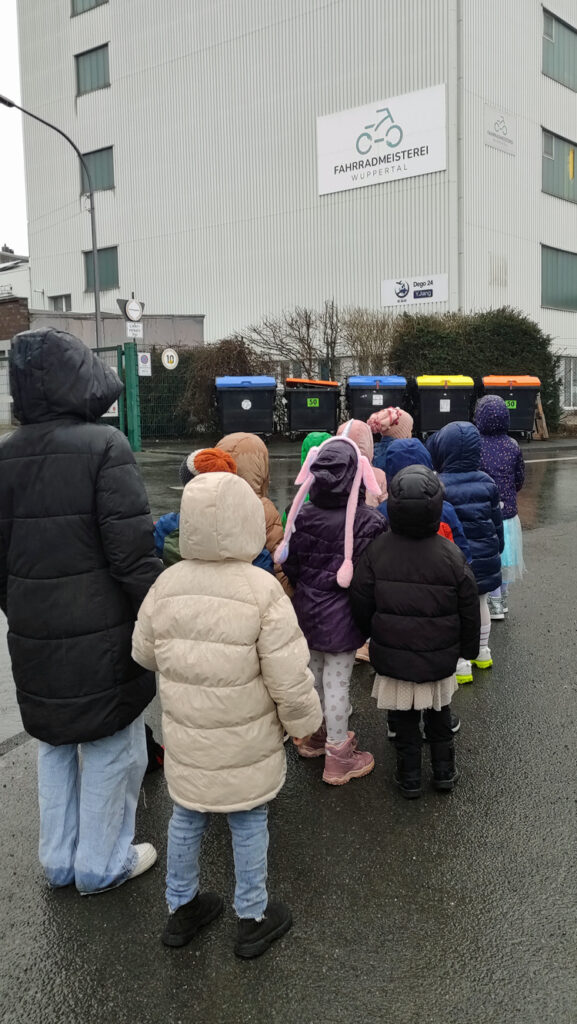 Eine Kindergruppe geht zu einem Industriegebaeude
