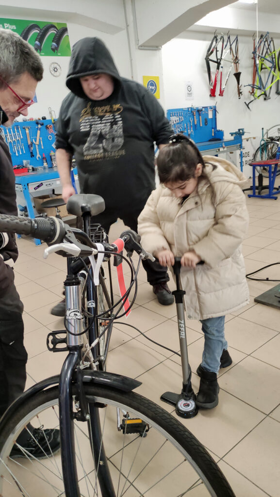 Ein Kind betaetigt eine Standluftpumpe, um einen Fahrradreifen aufzupumpen