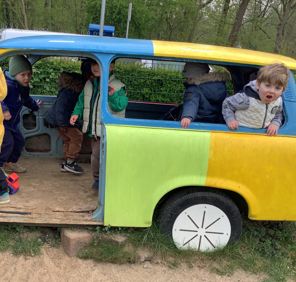 Kinder spielen in einem bunten Auto auf einem Spielplatz