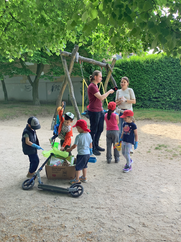 Eine Erzieherin in einer Gruppe von Kindern spricht in das Mikrofon eines Radioreporters