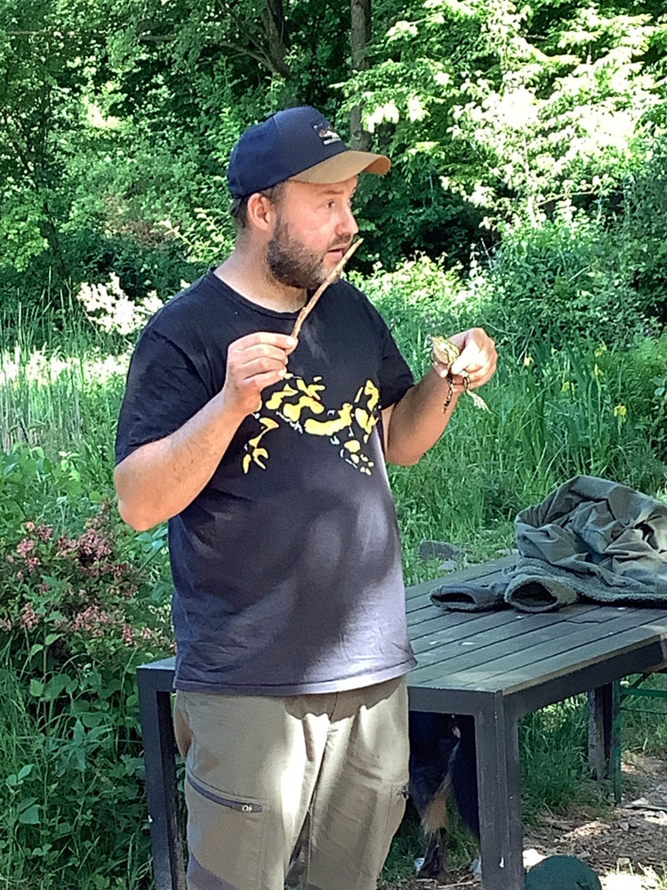 Ein Mann haelt einen Frosch in den Haenden und erzaehlt dazu etwas