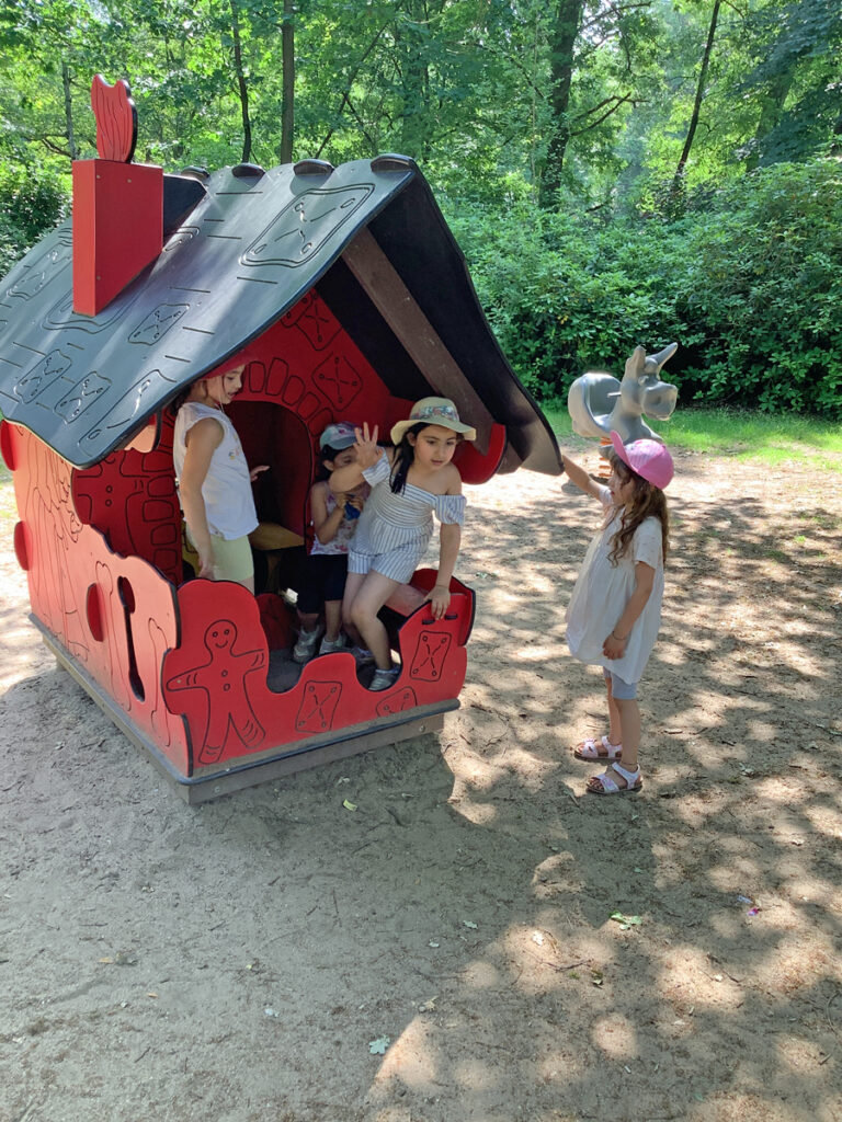 Bei warmem Sommerwetter spielen Kinder in einem kleinen Haus auf auf einem Spielplatz