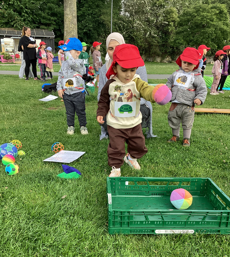 Ein Kind wirft eine bunten und weichen Ball in eine Kiste