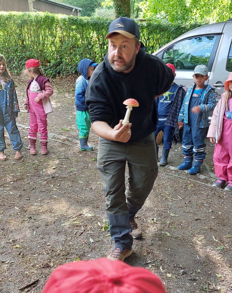Der Leiter der Wildnisschule Ruhr zeigt den Kita-Kindern einen giftigen Fliegenpilz