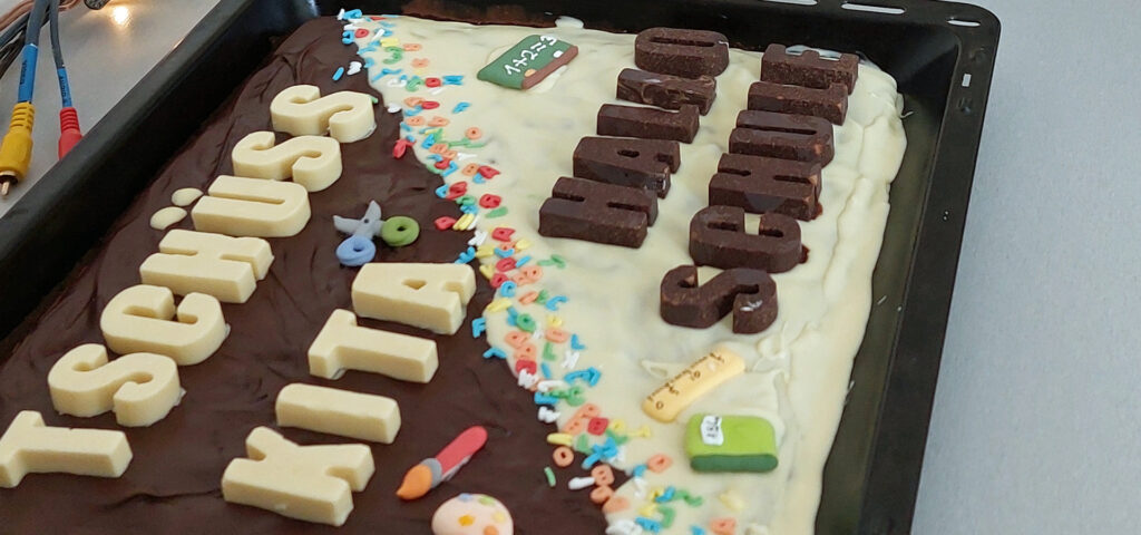 Auf einem Backblech mit Kuchen steht in Schokoladen-Buchstaben Tschuess Kita Hallo Schule