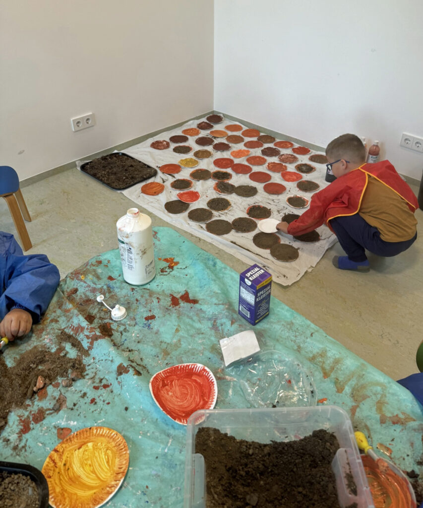 Kinder in der Kita malen Pappteller bunt und braun an