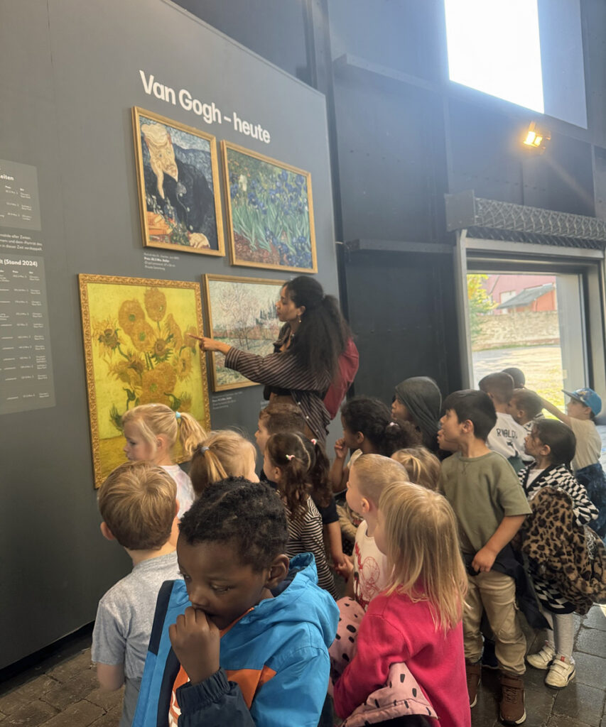 Eine Kindergruppe steht im Visiodrom Museum vor Bildern von Vincent van Gogh