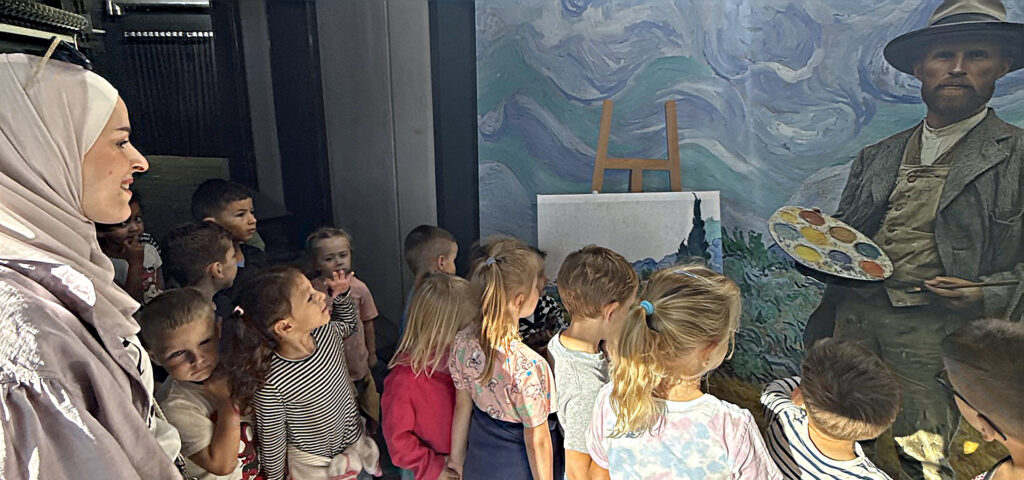 Kinder aus der CVJM-Kita stehen im Eingangsbereich des Visiodroms in Wuppertal vor einer Abbildung des Malers Vincent van Gogh