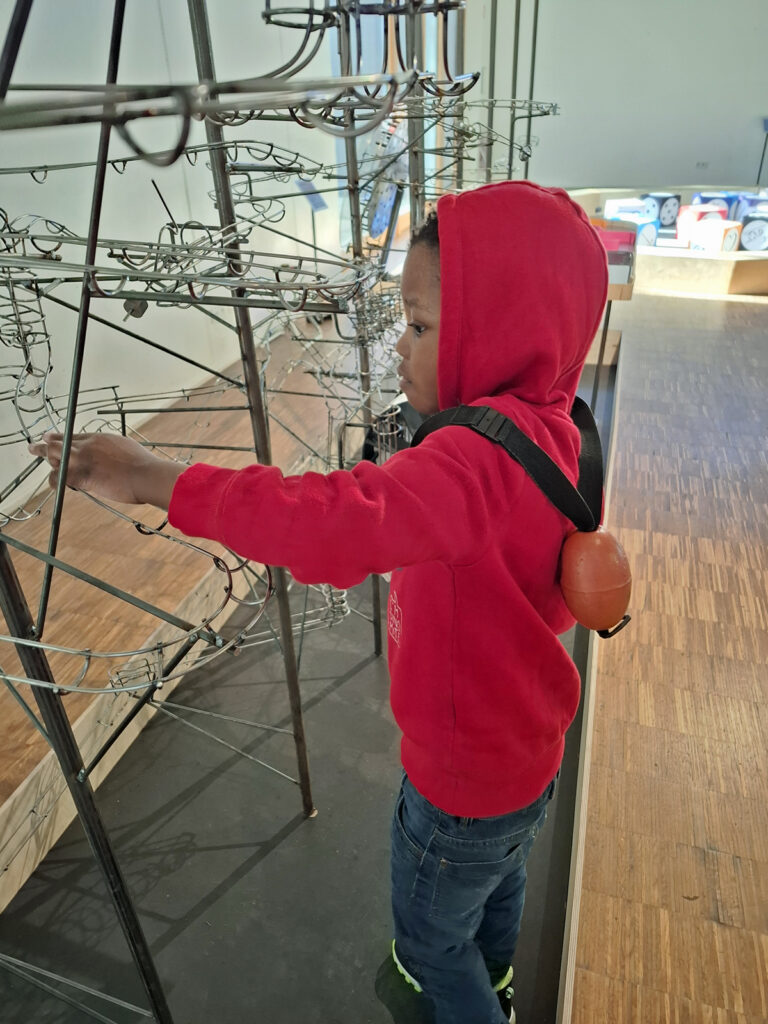 Ein Kind experimentiert an einem stahlgeruest im akki museum duesseldorf