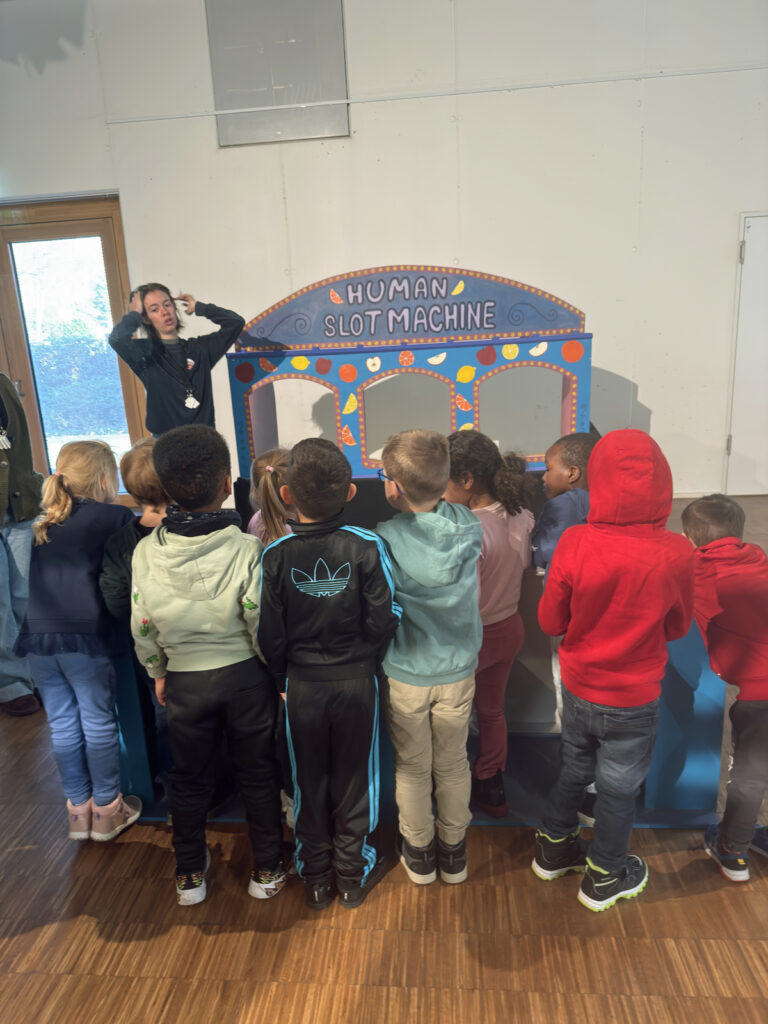 eine mitarbeiterin im akki museum erklaert den Kita-Kindern die human slot machine