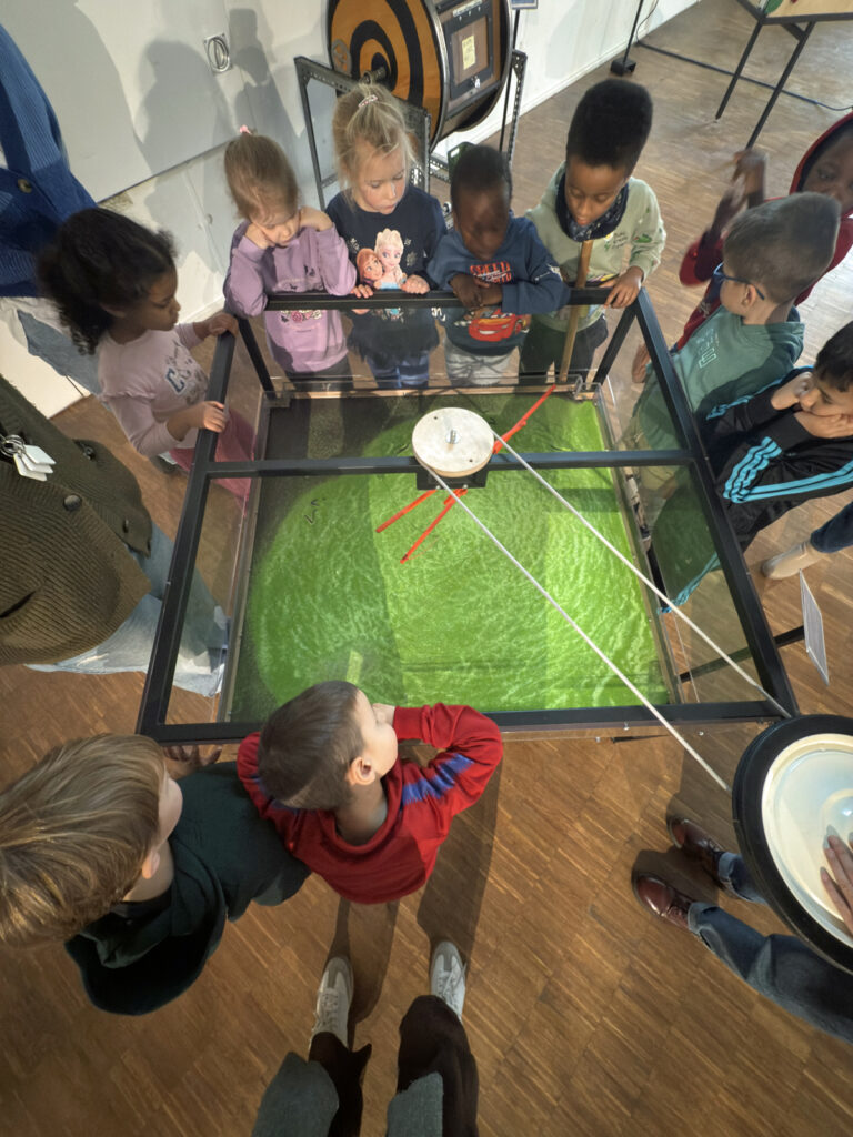 Kinder stehen im Museum in Duesseldorf um einen Experimentiertisch herum