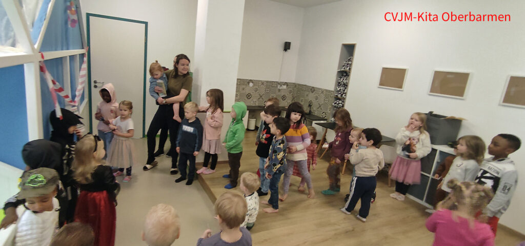 Kinder und eine Erzieherin haben sich zur Einweihungsfeier im Theaterraum der CVJM Kita Oberbarmen versammelt