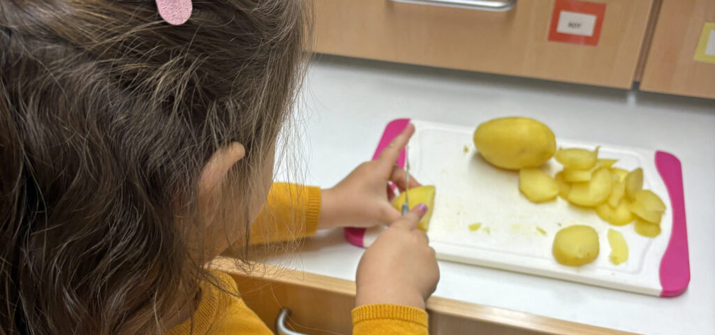 Ein Kind schneidet gekochte Kartoffeln in Scheiben