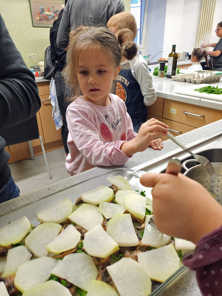 Kinder schickten Gemuese und weitere Zutaten in grosse Auflaufformen