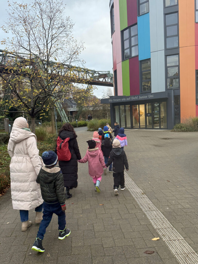 Kinder und Erzieherinnen gehen zum Eingang der Junior Uni in Wuppertal, ein Gebaeude mit bunter Fassade