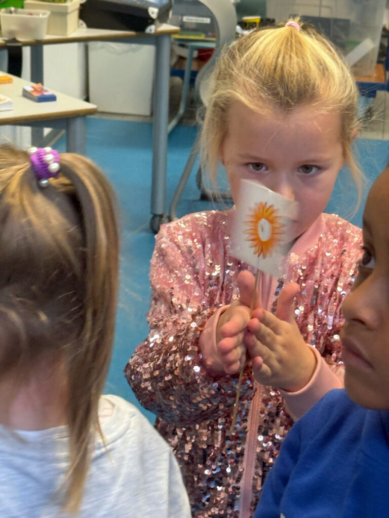 Ein Kind dreht seine Wunderscheibe und schaut wie die beiden selbstgemalten Bilder miteinander verschmelzen