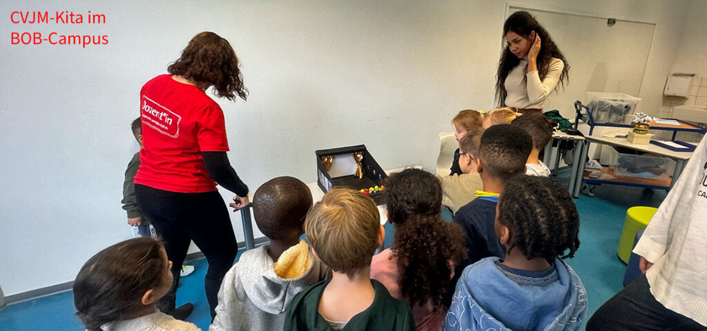 Die Dozentin in der Junior Uni zeigt Kindern ein Modell eines Theaters