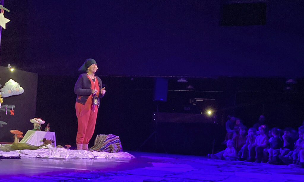 Gebannt lauschen die Kinder der Maerchenerzaehlerin im abgedunkelten Theaterraum