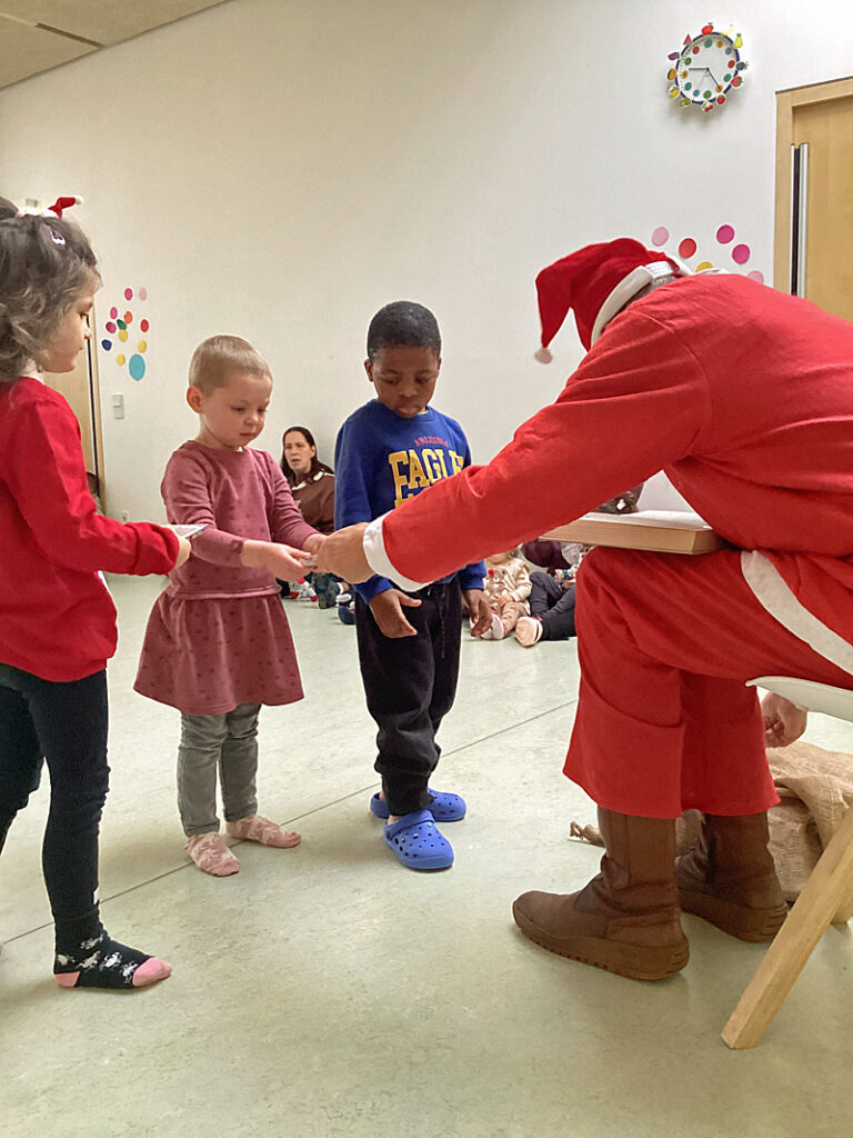 Der Nikolaus ueberreicht Kita-Kindern kleine Geschenke