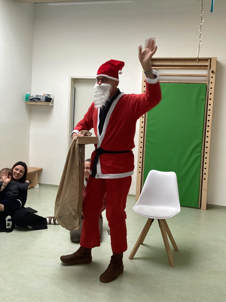 Der Nikolaus ist von seinem Stuhl aufgestanden und winkt den Kindern zum Abschied zu