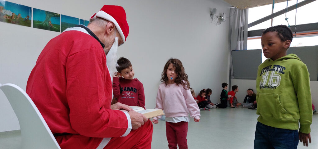Kinder stehen vor dem Nikolaus und hoeren erstaunt zu was er aus seinem goldenen Buch vorliest
