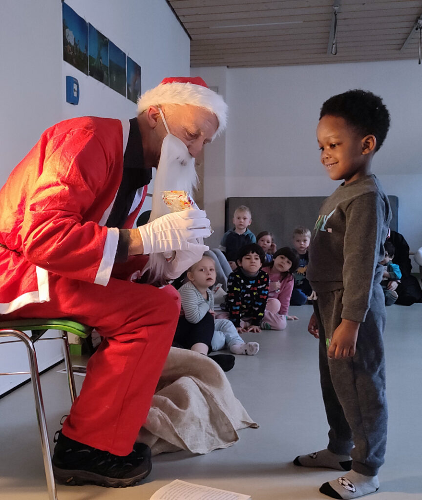Ein Kind freut sich ueber das Geschenk das ihm der Nikolaus ueberreicht
