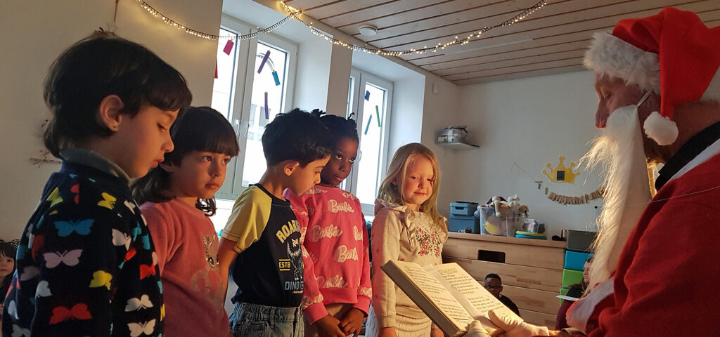 Der Nikolaus ist gekommen und die Kinder hoeren was er aus einem grossen Buch vorliest