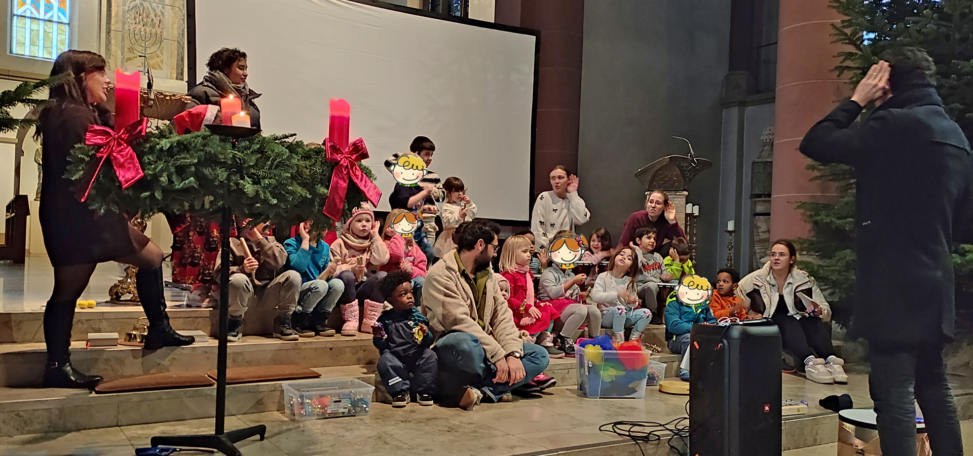 Kinder und Erwachsene sitzen auf Stufen im Altarraum der Kirche und singen ein Lied