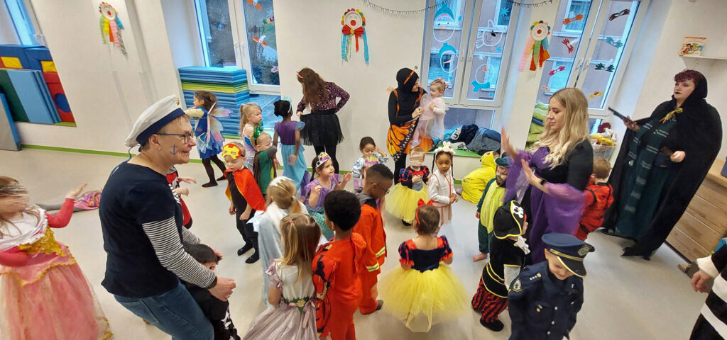 Kinder und Erwachsene sind verkleidet und tanzen im Raum