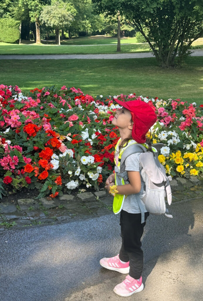 Ein Kind im Park neben einem Blumenbeet