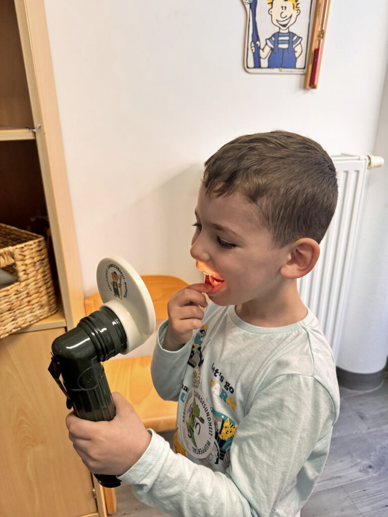 Ein Kind schaut sich in einem Spezial-Spiegel seine Zaehne an