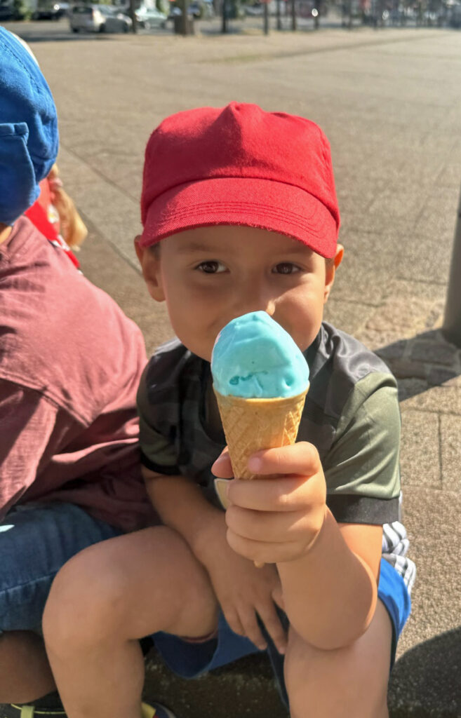 Ein Kind haelt ein Eis in der Waffel in der Hand