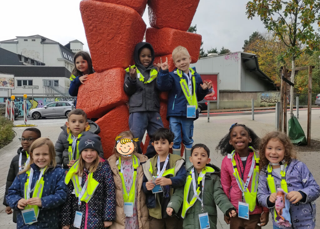 An einer Skulptur in Wuppertal posiert eine Gruppe Kita-Kinder