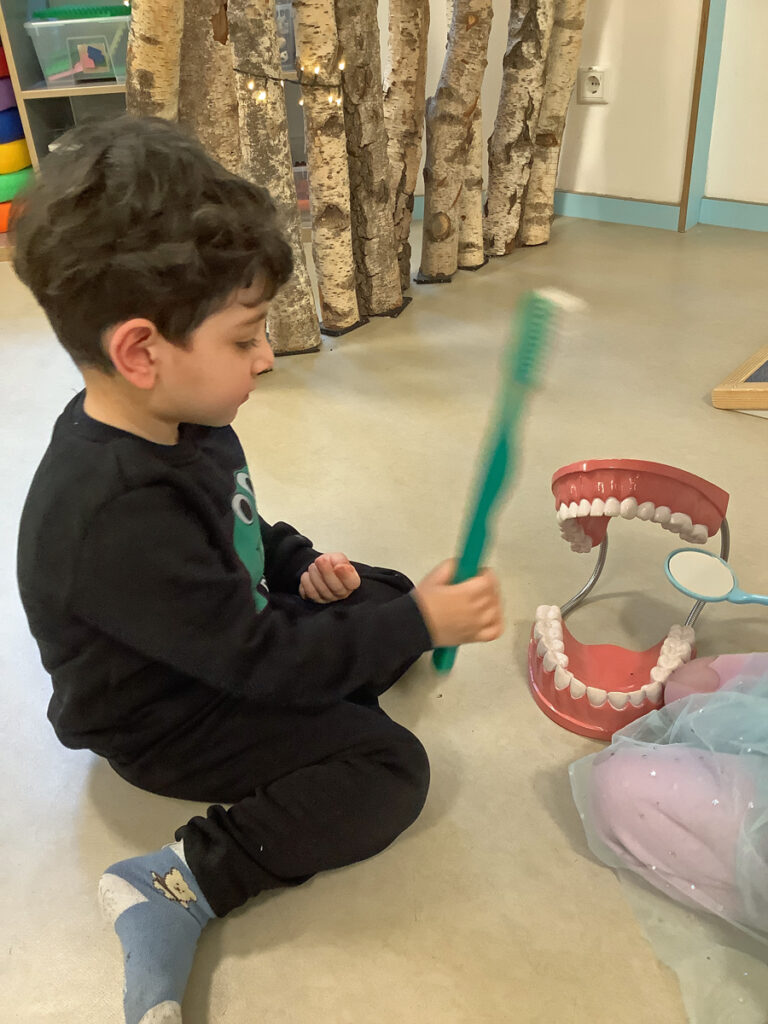 An einem grossen Gebiss ueben Kinder das Zaehneputzen